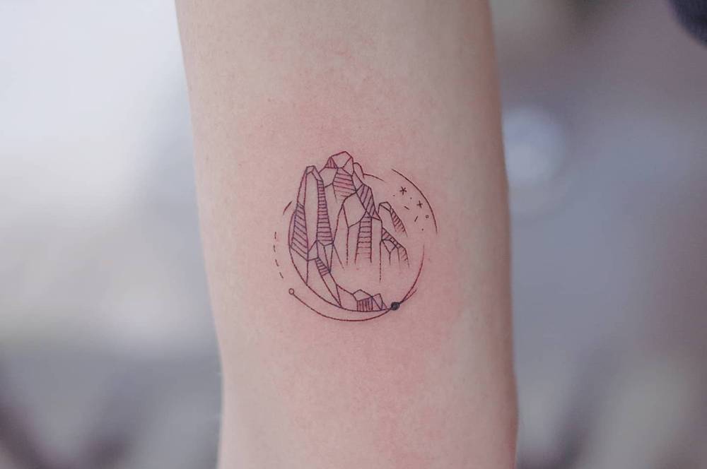 Mountains tattoo in fine line style located on the inner arm.