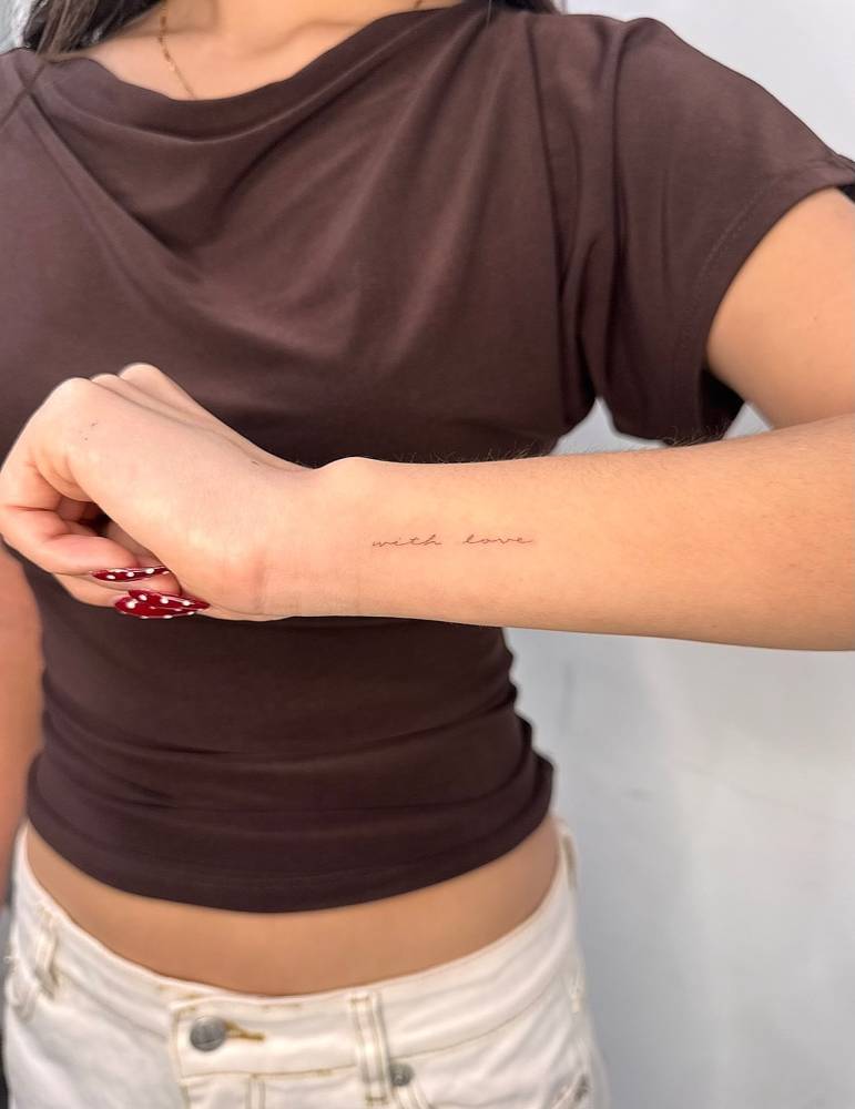 Handwritten font "with love" lettering tattoo located on the wrist.