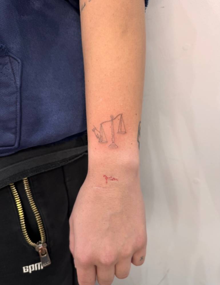Little scale tattoo in fine line style done on the wrist.