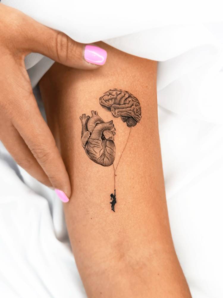 Heart vs brain balloons tattooed on the bicep.