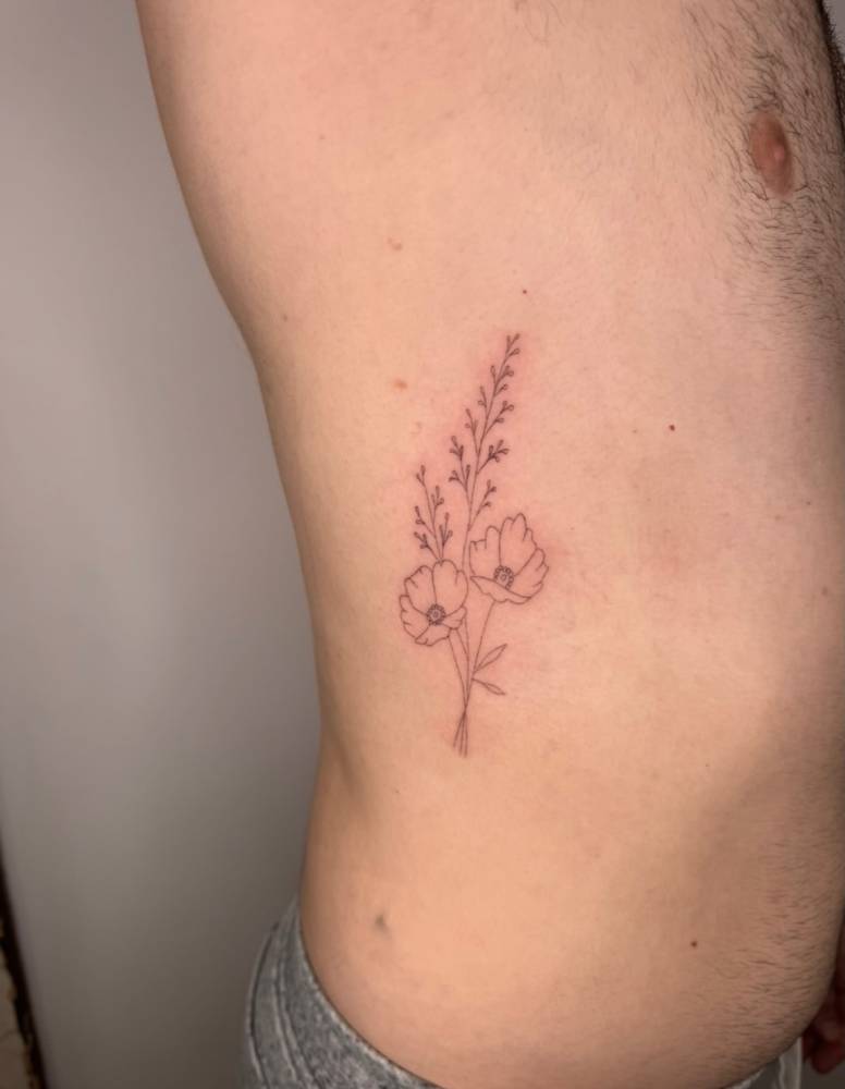 Fine line style poppy flowers tattoo located on the rib.