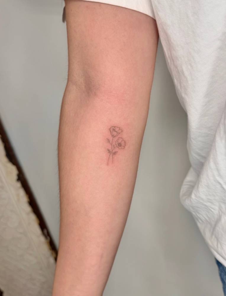 Poppy flowers tattoo placed on the inner forearm, fine line style.