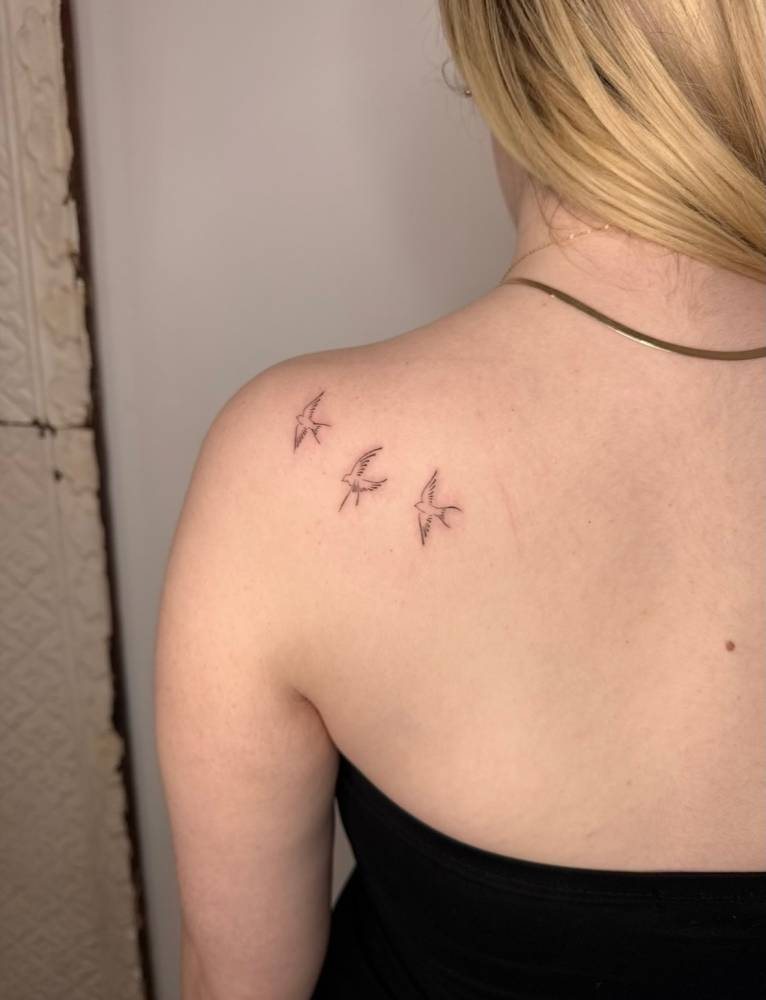 Flying swallows tattoo located on the shoulder blade.