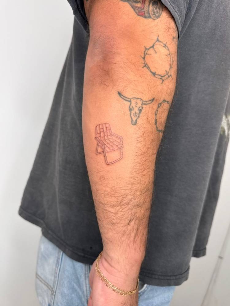 Beach chair tattoo in fine line style done on the forearm.