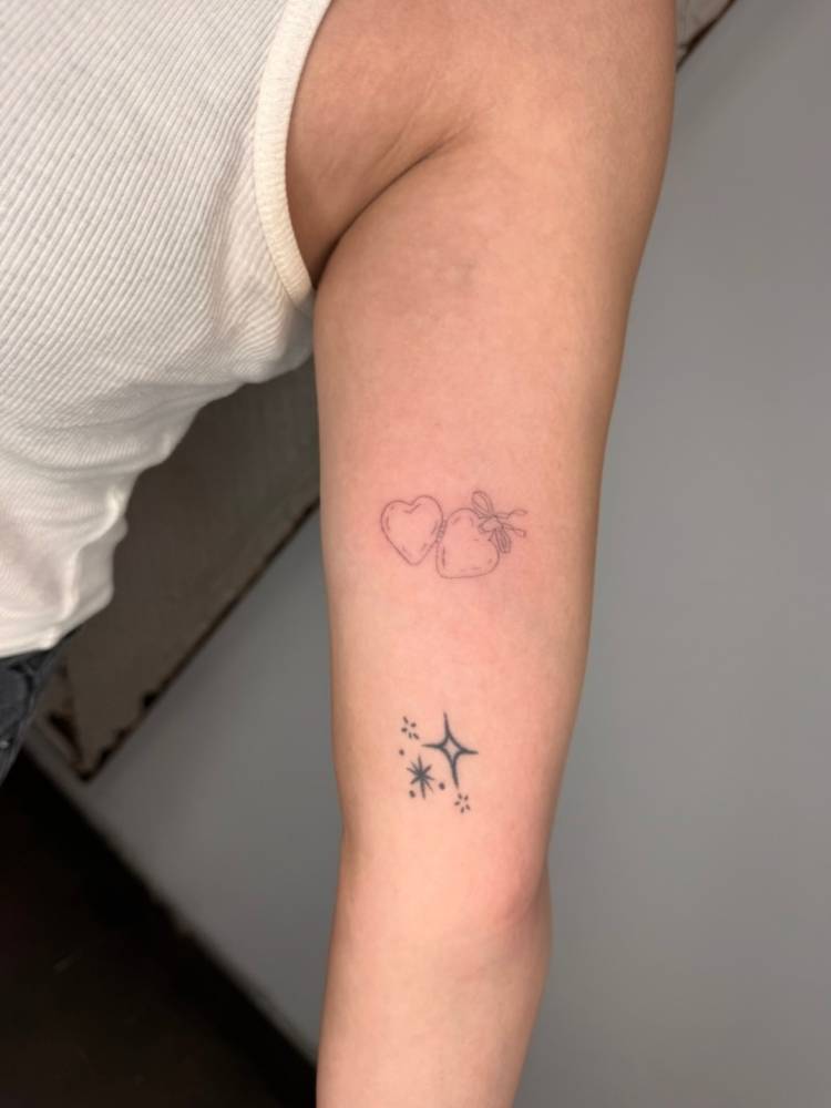 Heart pendant tattoo located on the inner arm, done in fine line style.