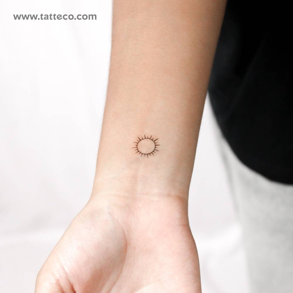 Small shining sun temporary tattoo located on the wrist.