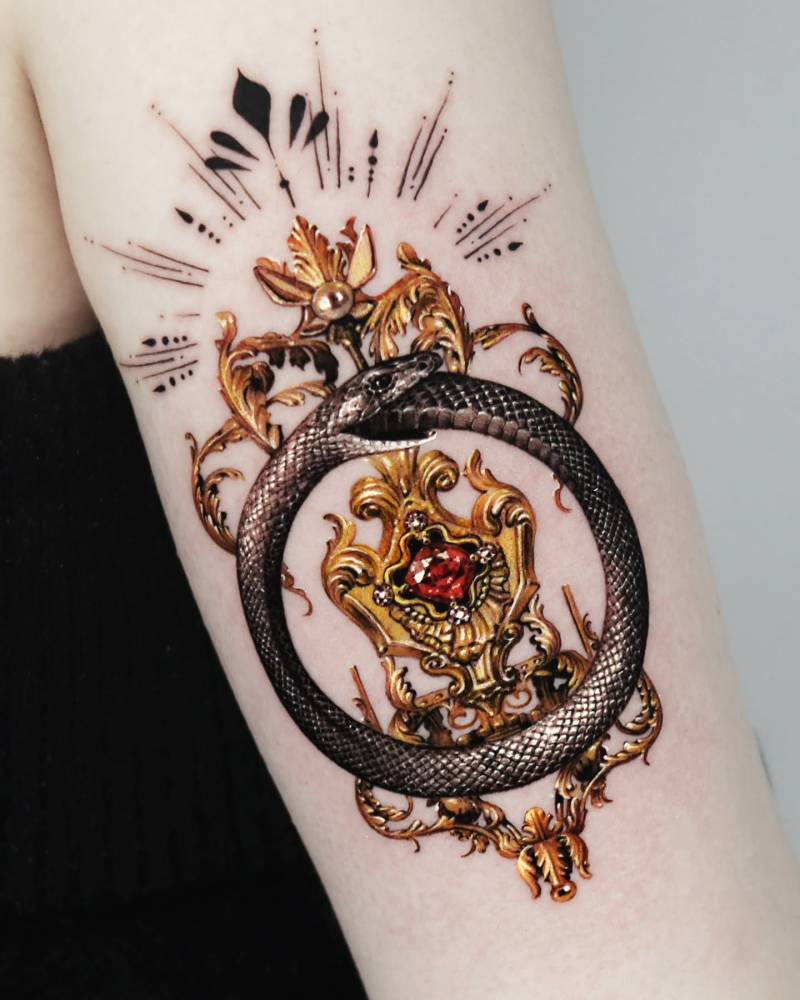 Snake ouroboros jewellery tattoo located on the tricep.