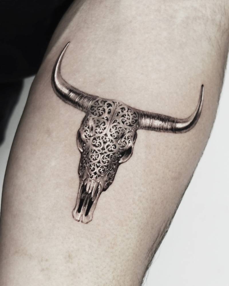 Metallic bull skull tattoo located on the inner forearm, micro-realistic style.