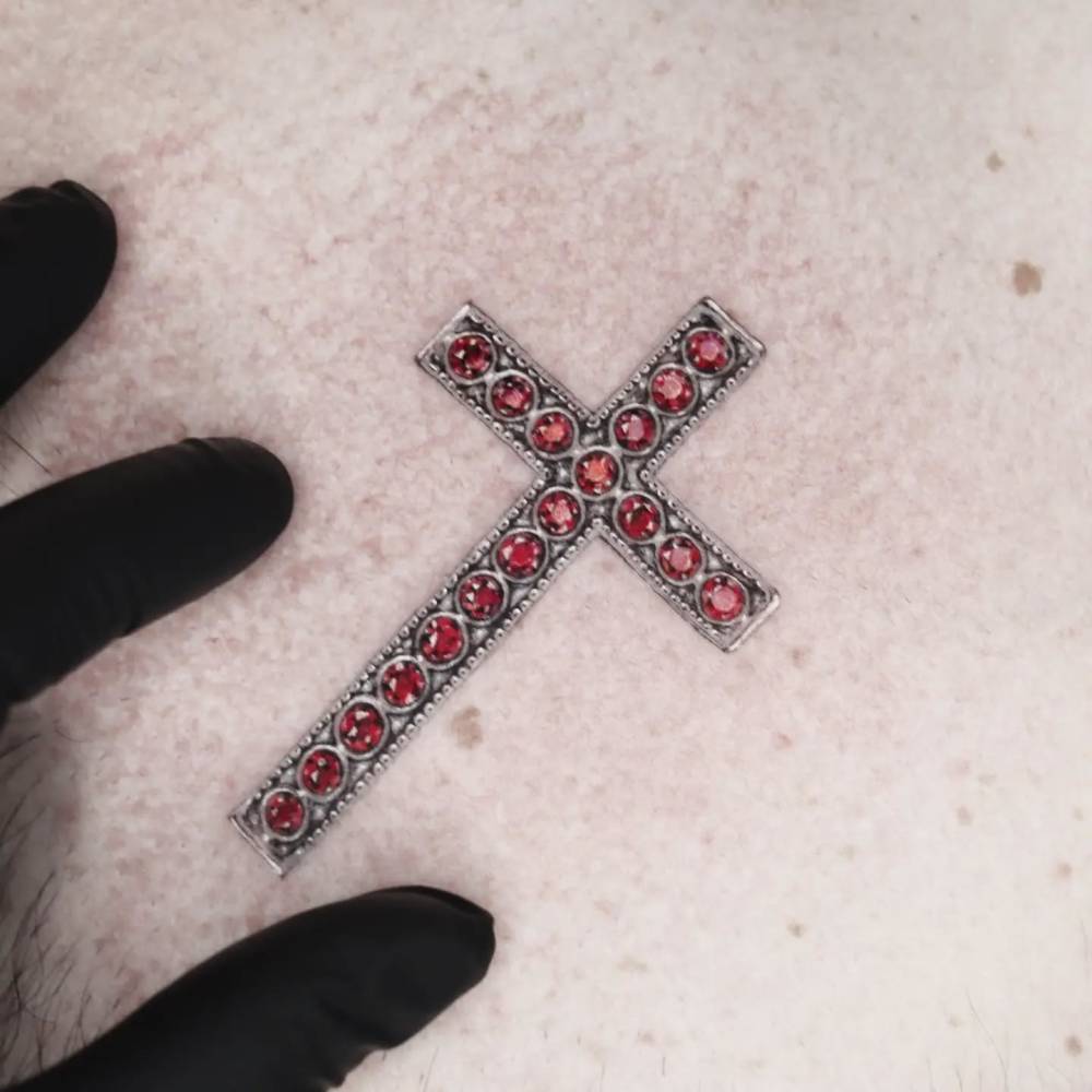 Christian cross jewellery tattoo located on the chest.