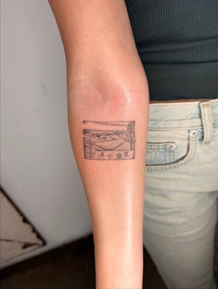 Landscape tattoo in illustrative style located on the inner forearm.