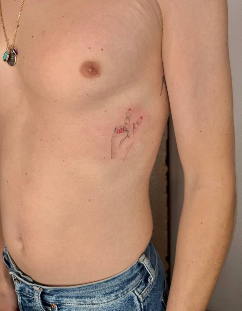 V sign tattoo in illustrative style located on the rib.