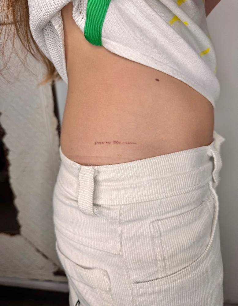 "Free as the ocean" lettering tattoo handwritten on the hip.