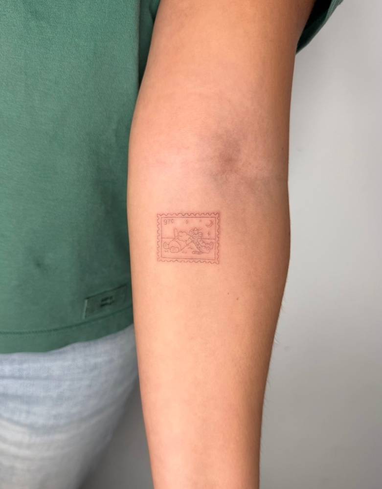 Pooh Bear and Tigger stamp tattoo located on the inner forearm.