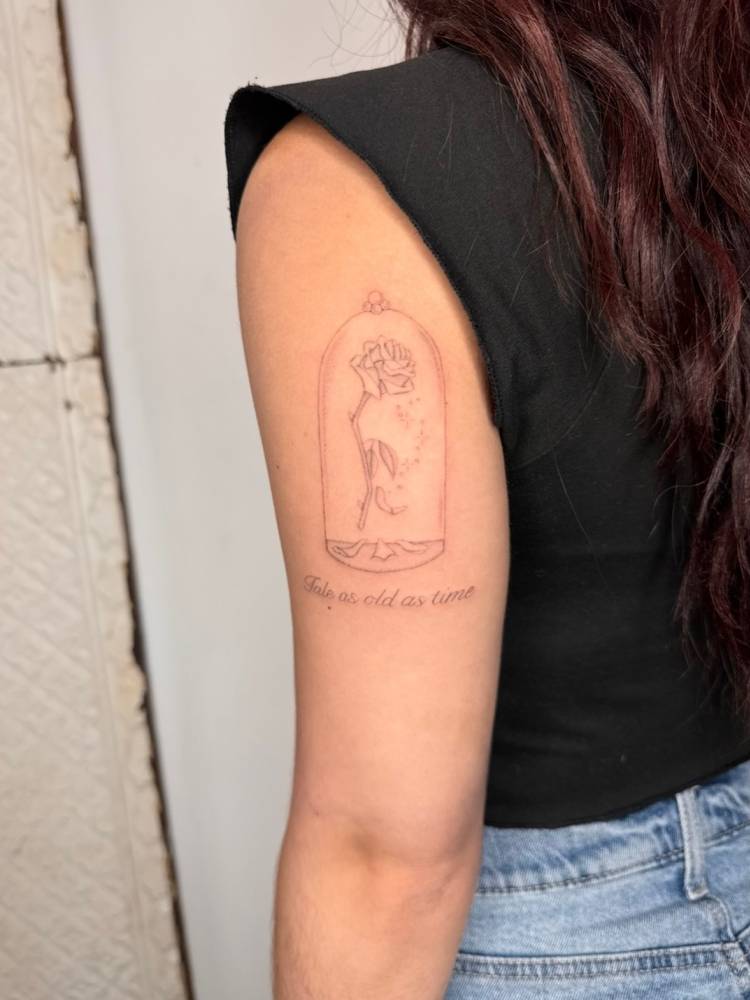 "Tale as old as time" and rose in a glass dome tattooed on the tricep.