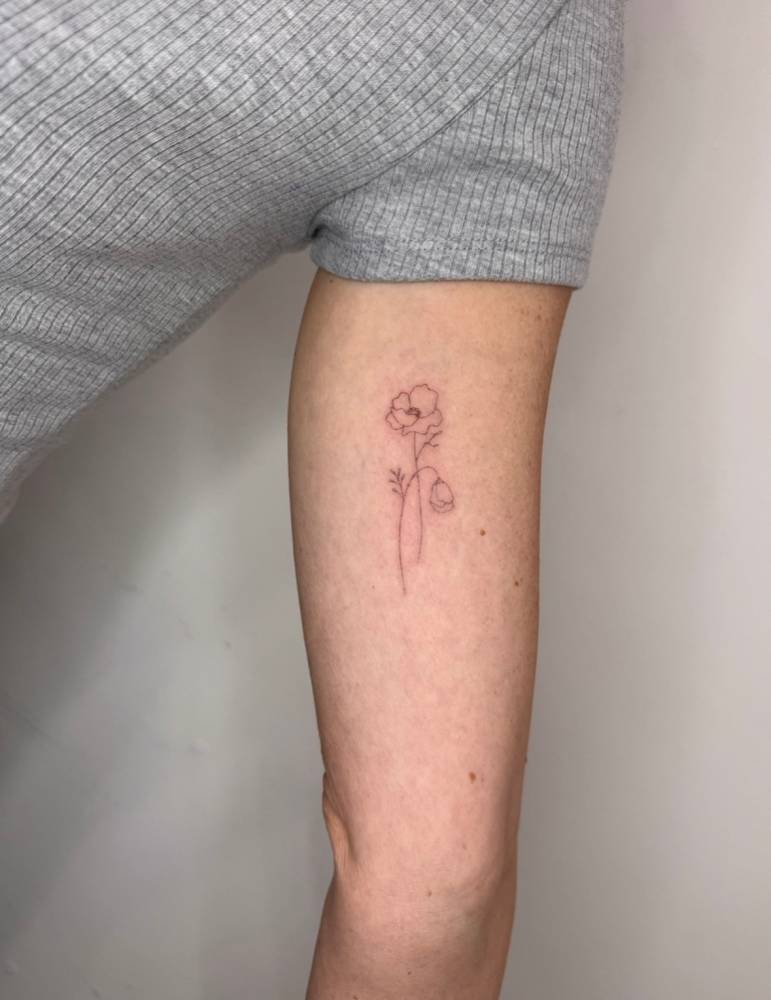 Single needle poppy flower tattoo located on the inner arm.
