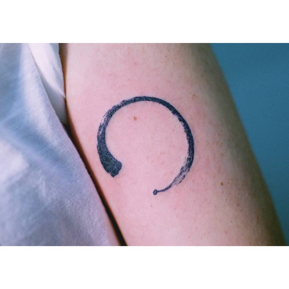 Enso tattoo located on the tricep, watercolor style.