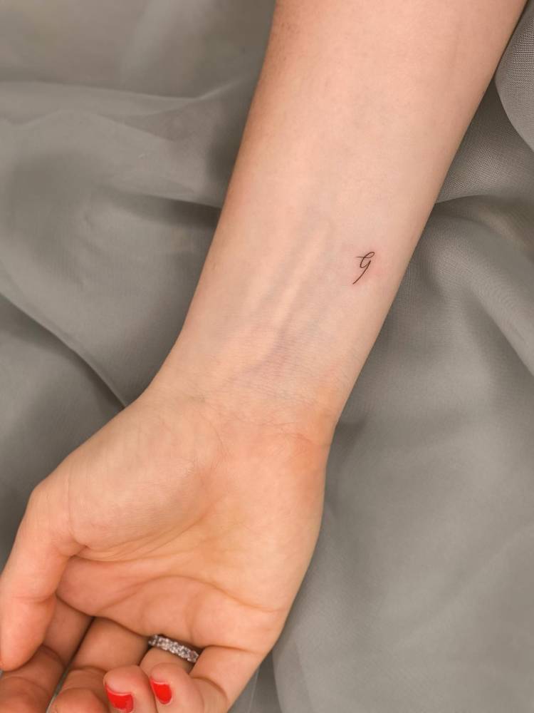 Handwritten font letter "B" tattoo located on the wrist.