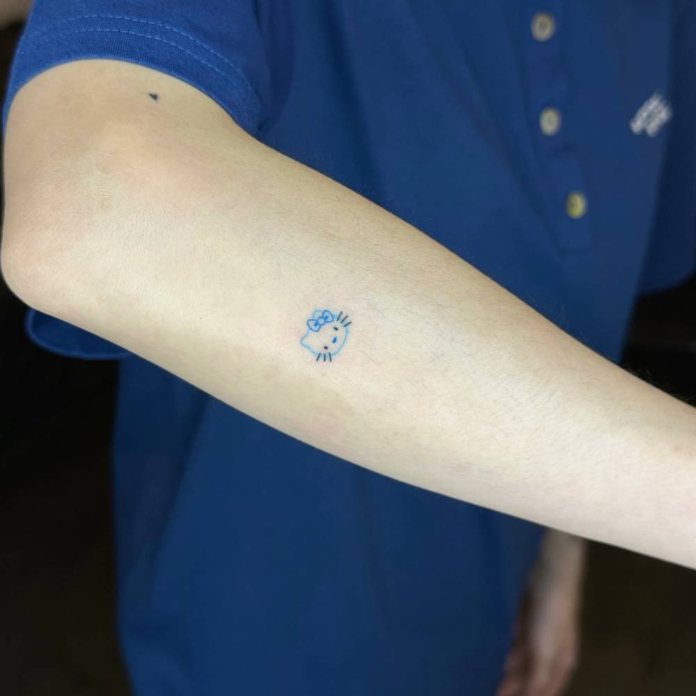 Tiny Hello Kitty tattoo hand poked on the forearm.