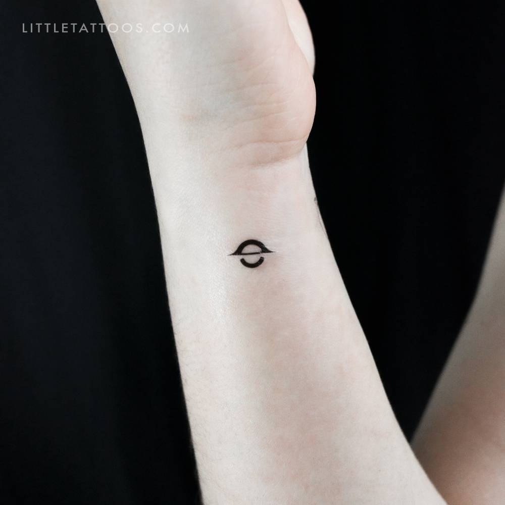 Minimalistic style black hole temporary tattoo located on the wrist.