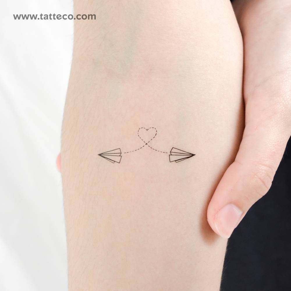 Two paper airplanes flying temporary tattoo located on the inner forearm.