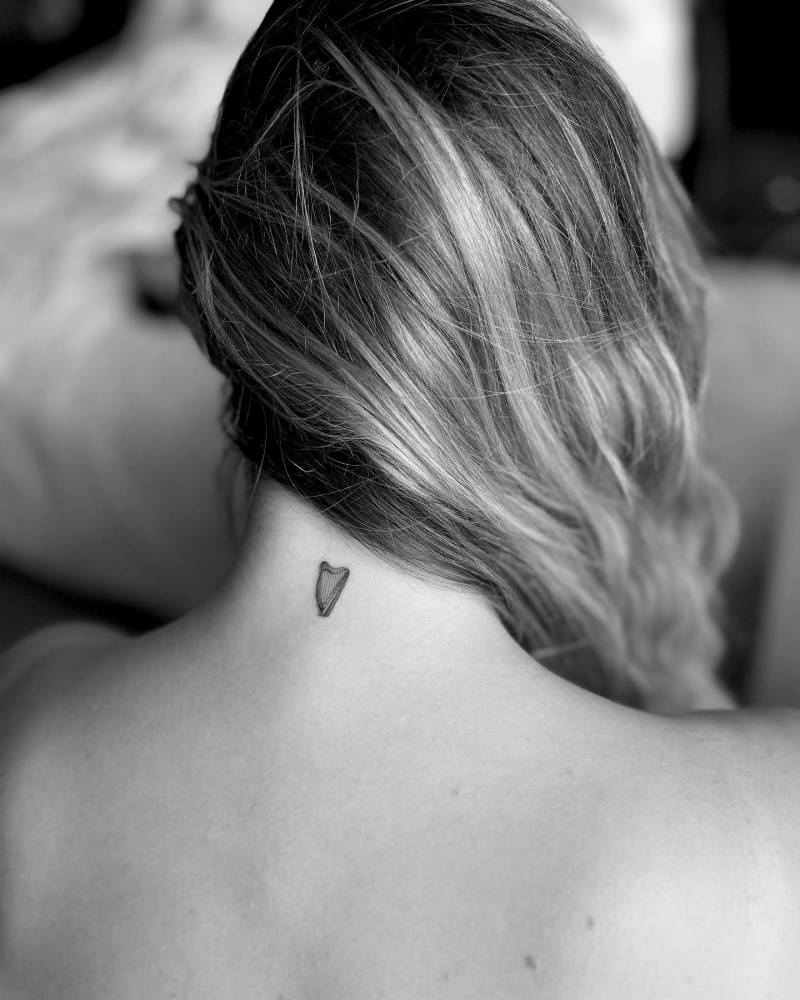 Illustrative style harp tattoo located on the back of the neck.