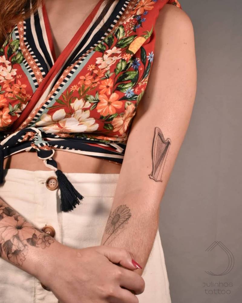 Harp tattoo in fine line, located on the upper arm.
