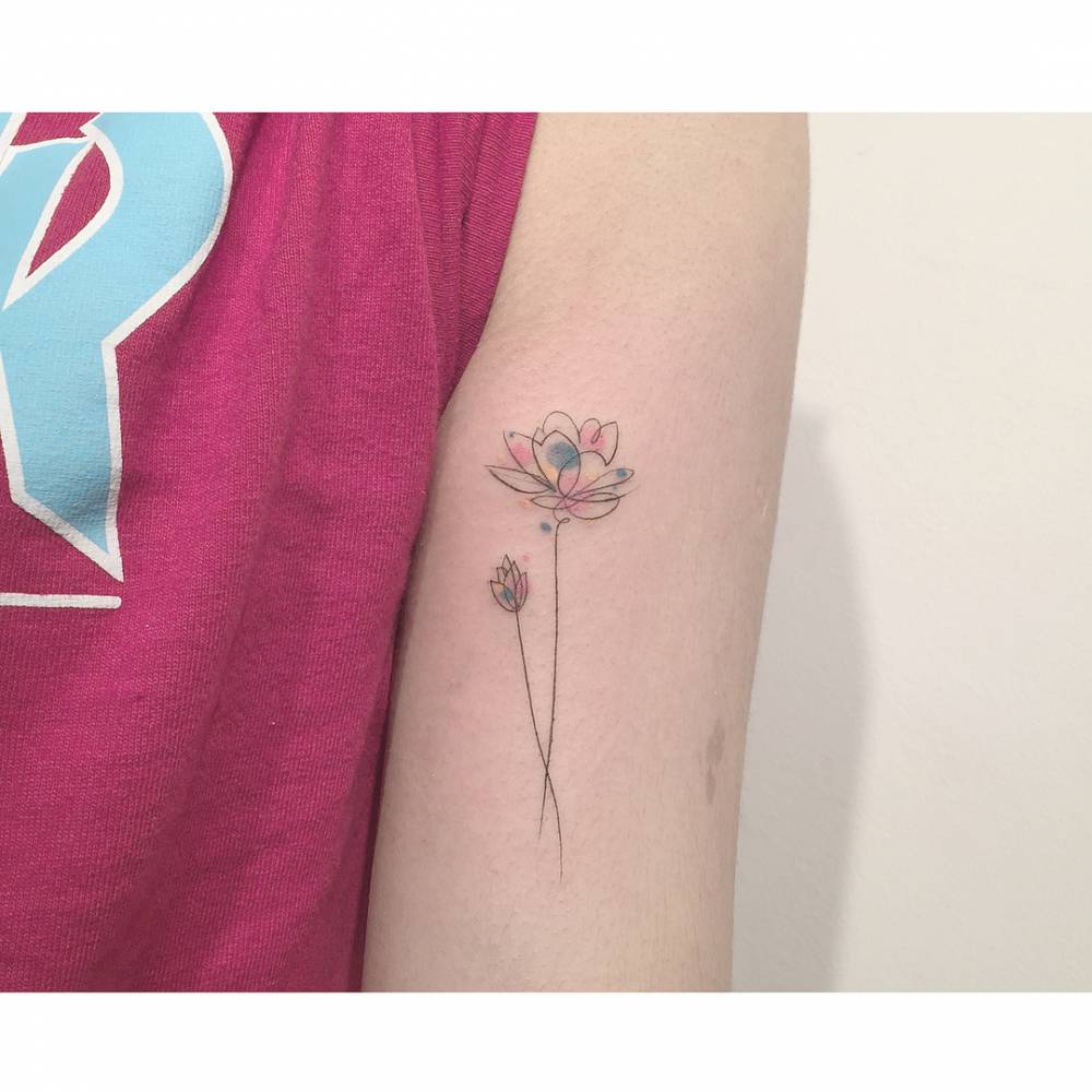 Lotus flower and tulip tattooed on the bicep, illustrative style.