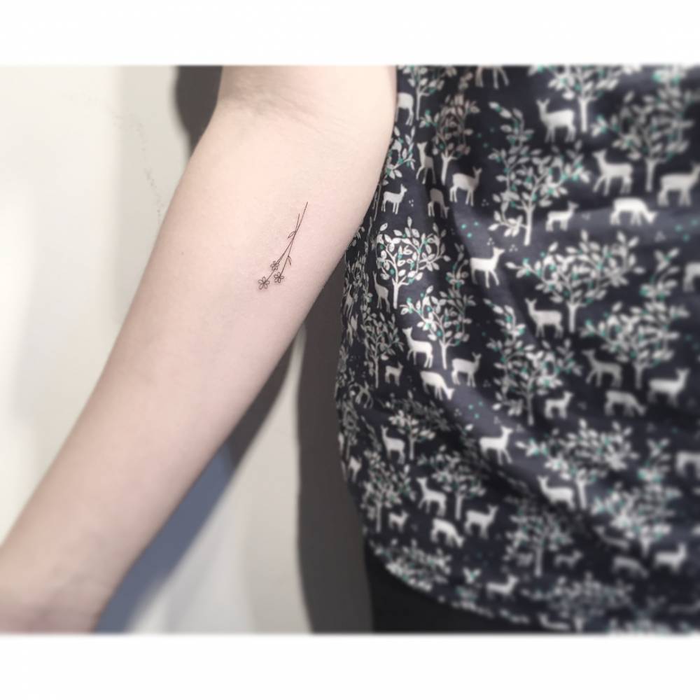 Little flowers tattoo located on the inner forearm, done in fine line style.
