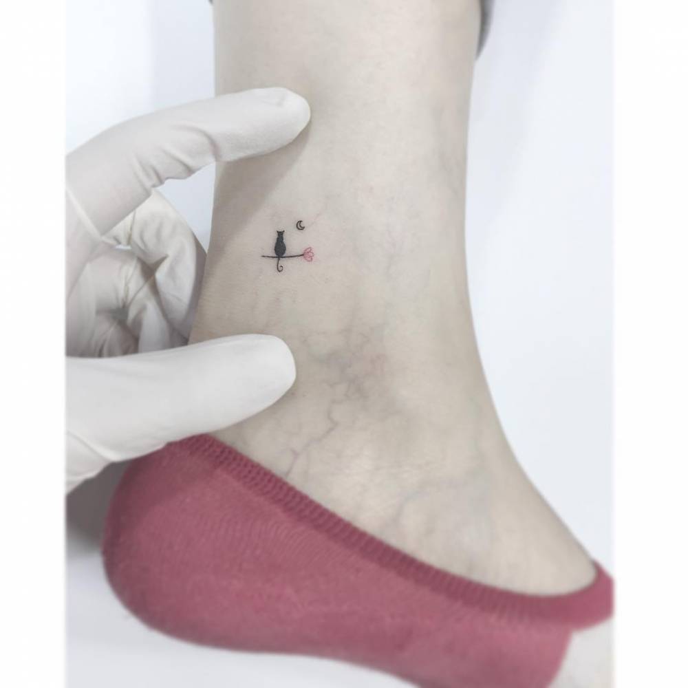 Black cart, flower and moon tattoo located on the ankle.