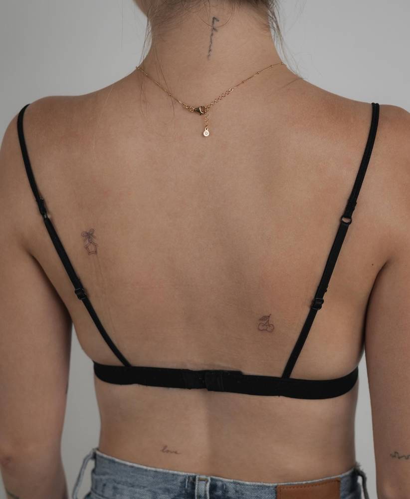 Fine line style star pendant and cherries tattooed on the back.