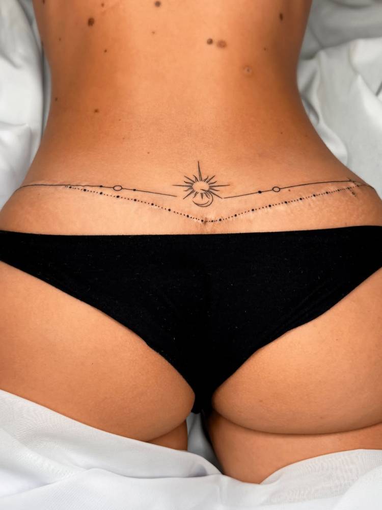 Ornamental sun and moon tattoo located on the lower back.