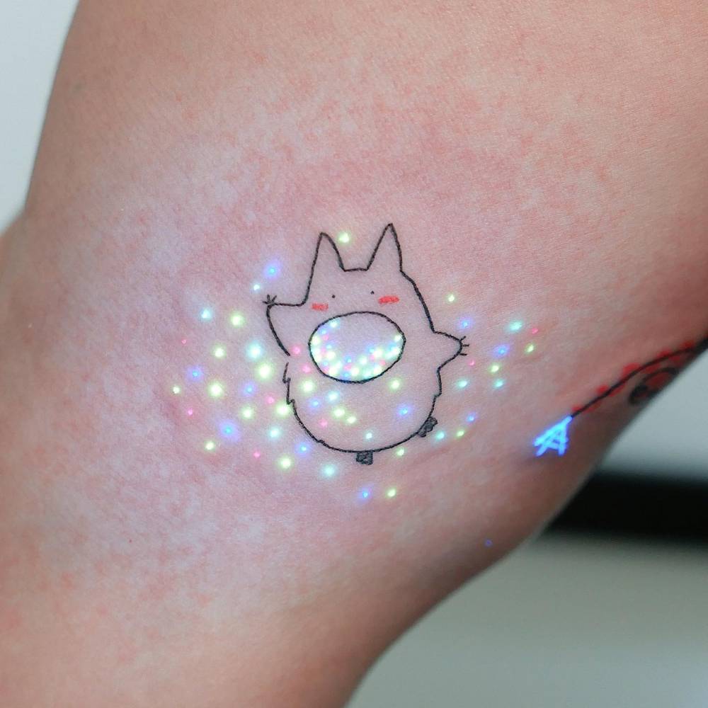 Chuu Totoro tattoo in cartoon style located on the inner arm.