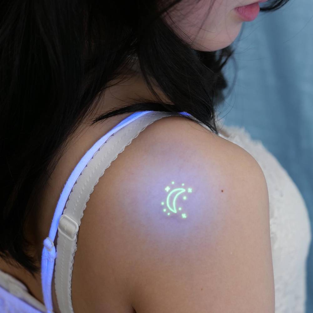 UV ink crescent moon and stars tattoo located on the shoulder blade.