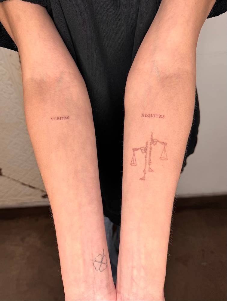 Words "veritas" and "aequitas" and scale tattooed on the inner forearms.