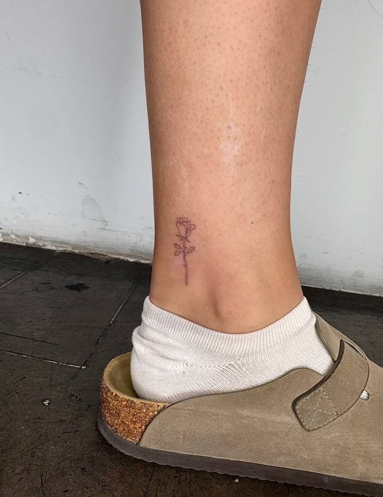 Single needle rose tattoo located on the ankle.