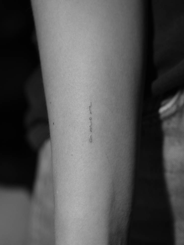 Word "amore" in handwritten font tattooed on the inner forearm.