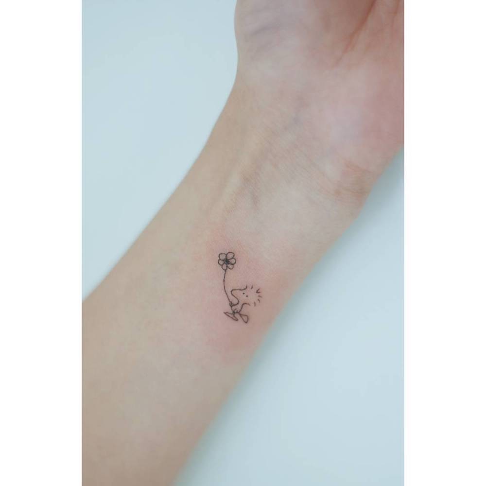 Woodstock holding and flower tattooed on the wrist, cartoon style.