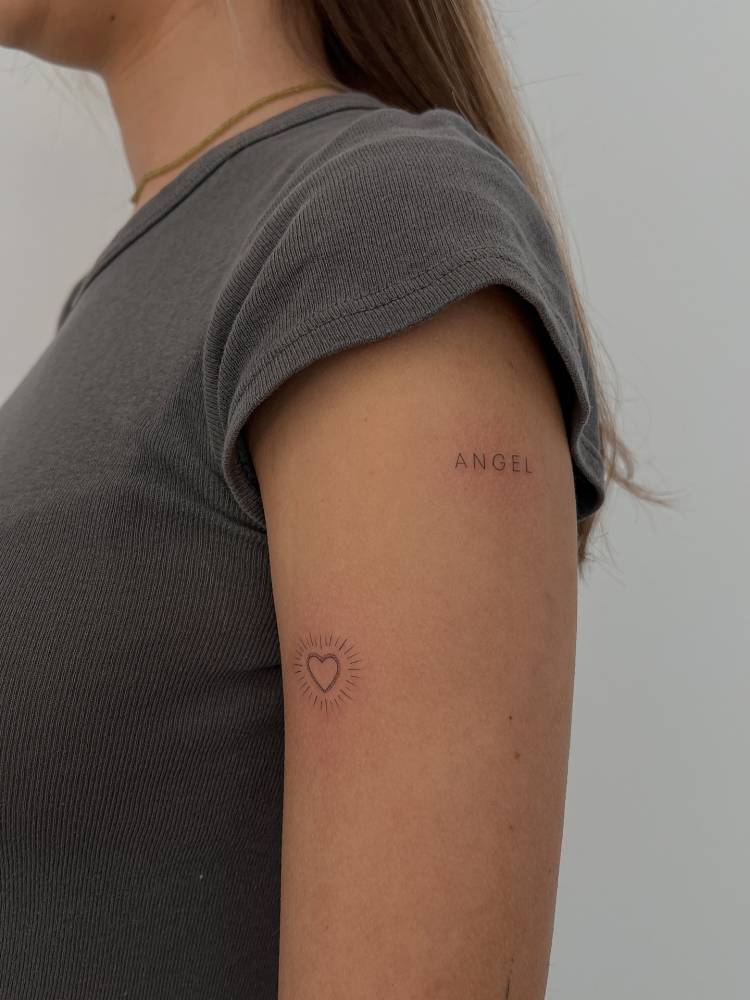 Shiny heart and word "angel" tattooed on the upper arm.