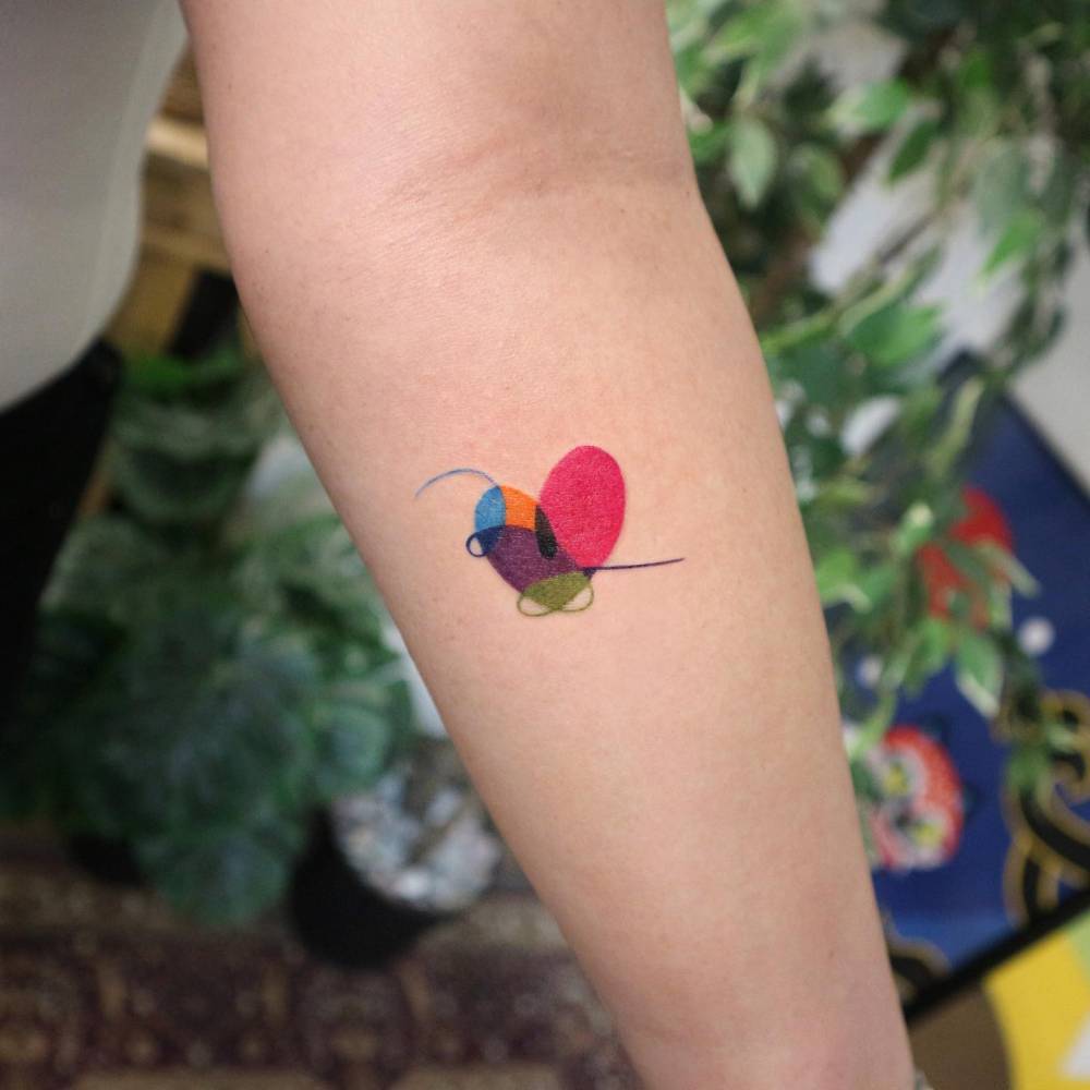 BTS heart tattoo in pop art style located on the inner forearm.