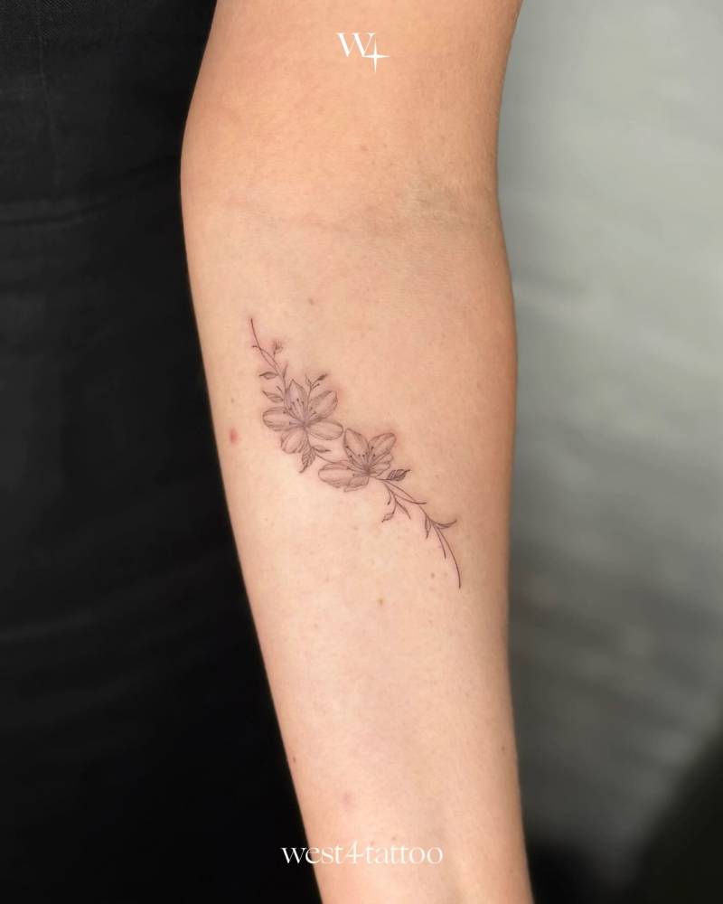 Fine line style cherry blossom tattoo located on the inner forearm.