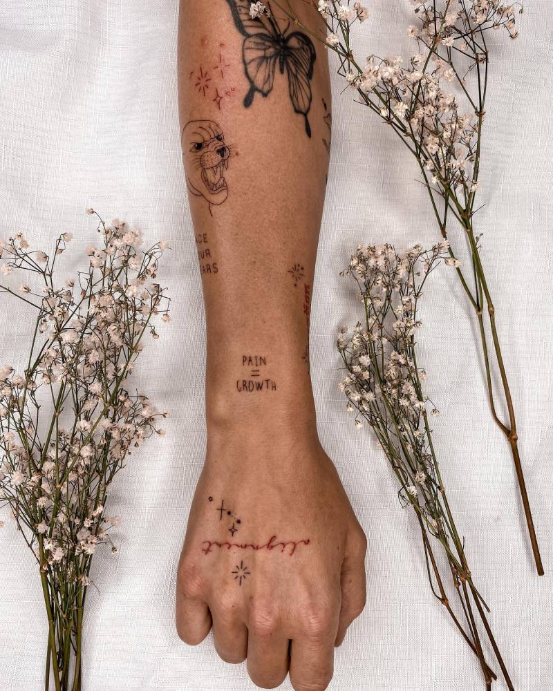 "Pain equals growth" lettering tattoo located on the wrist.