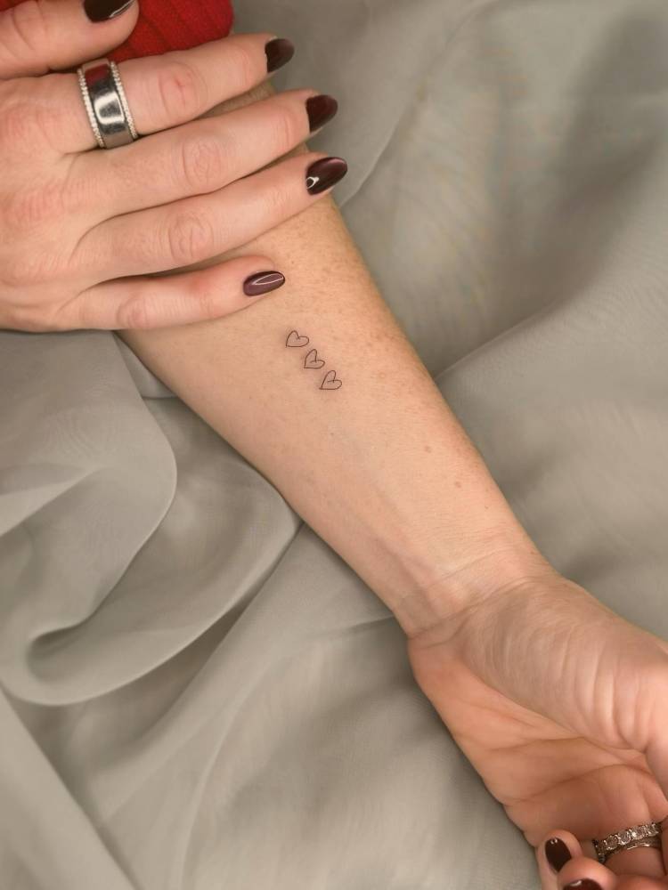 Minimalistic hearts tattoo located on the wrist.
