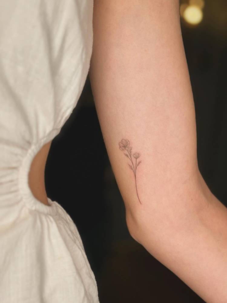 Little flowers tattoo located on the inner arm, done in fine line style.