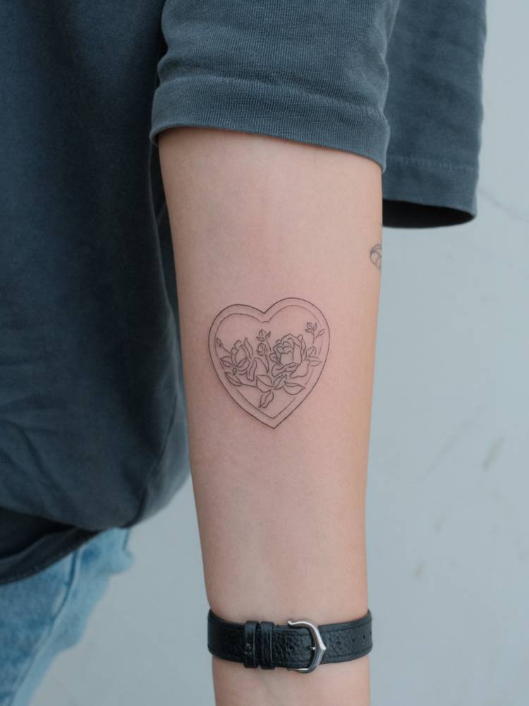 Roses and heart tattoo located on the inner forearm, done in fine line style.