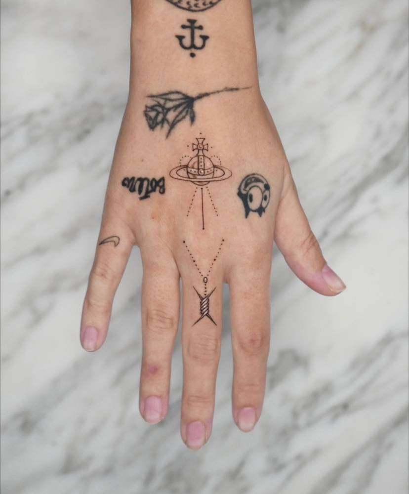 Vivienne Westwood orb and barbed wire pendant tattooed on the hand.
