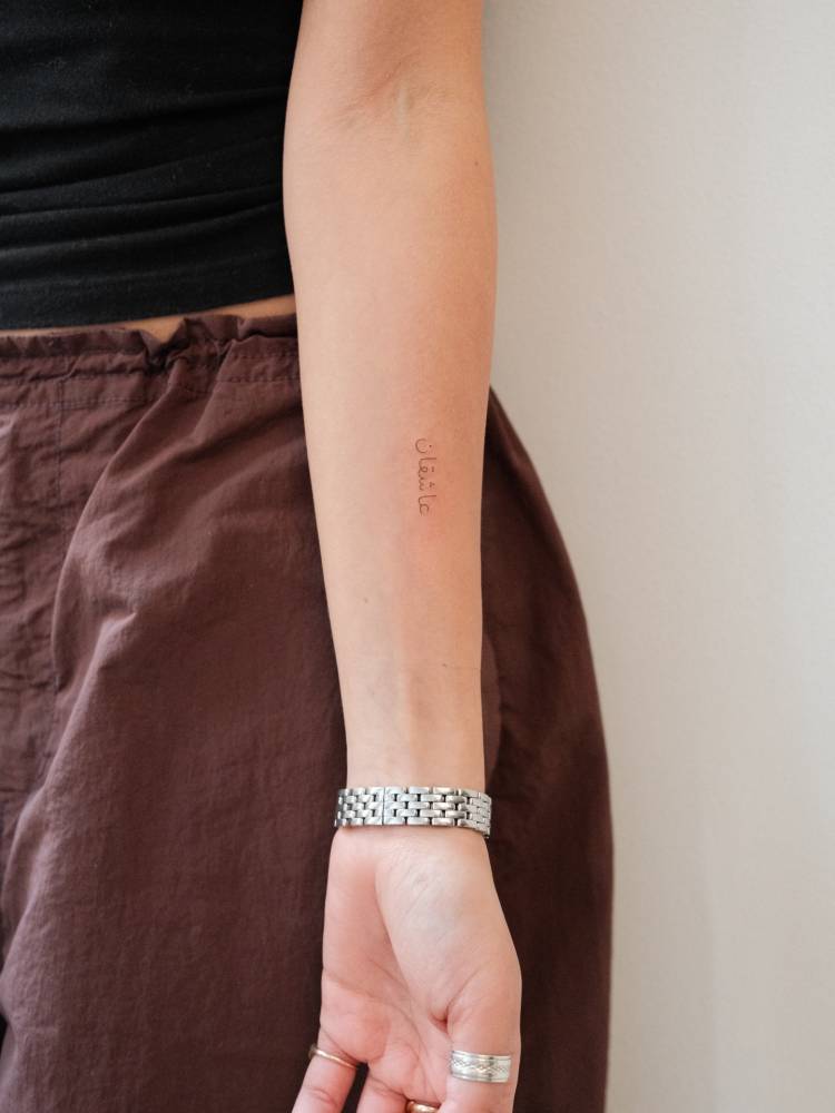 Arabic lettering tattoo located on the inner forearm.