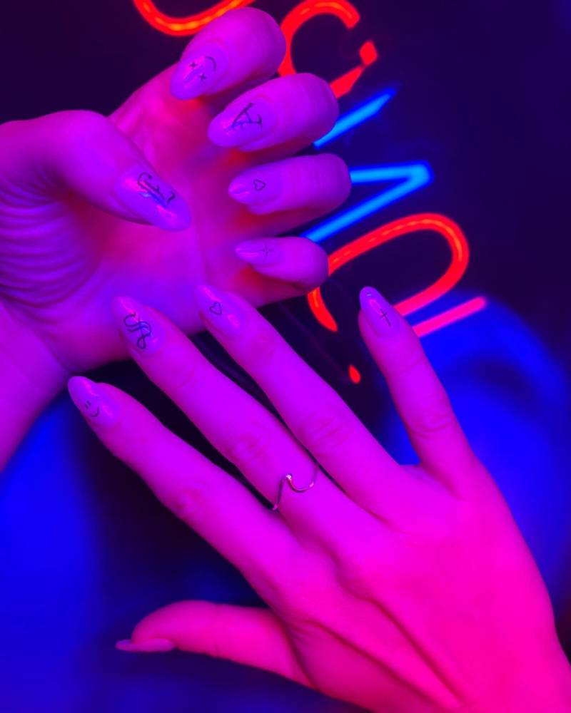 Gothic lettering tattooed on the fingernails.