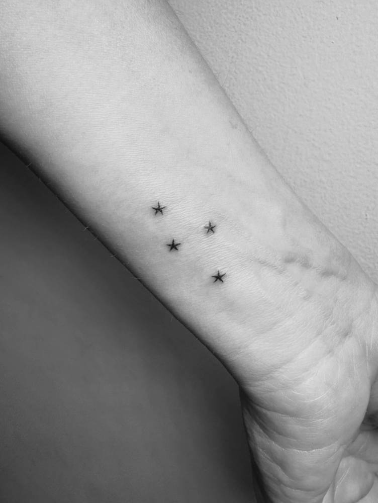 Minimalistic style four stars tattoo located on the wrist.