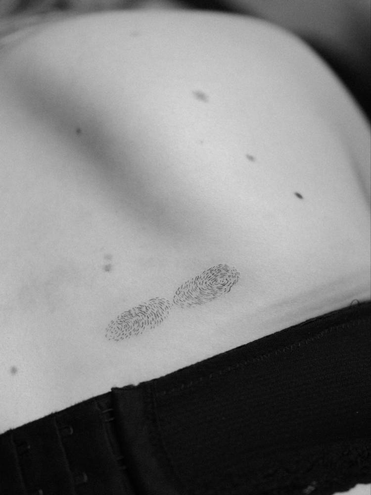 Finger prints tattoo located on the back.