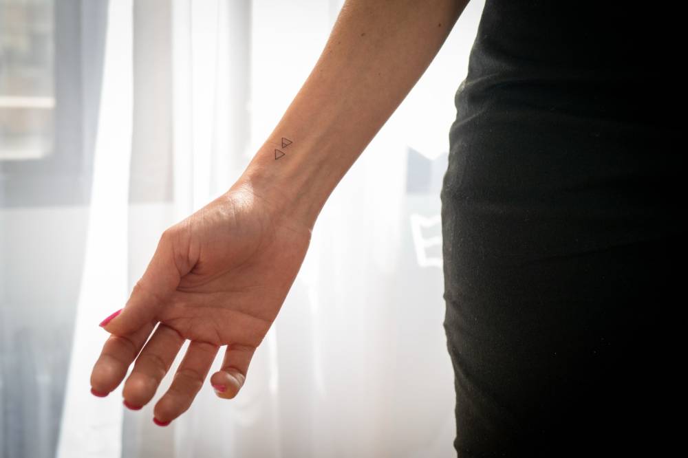 Fire and air alchemy symbols tattooed on the wrist.